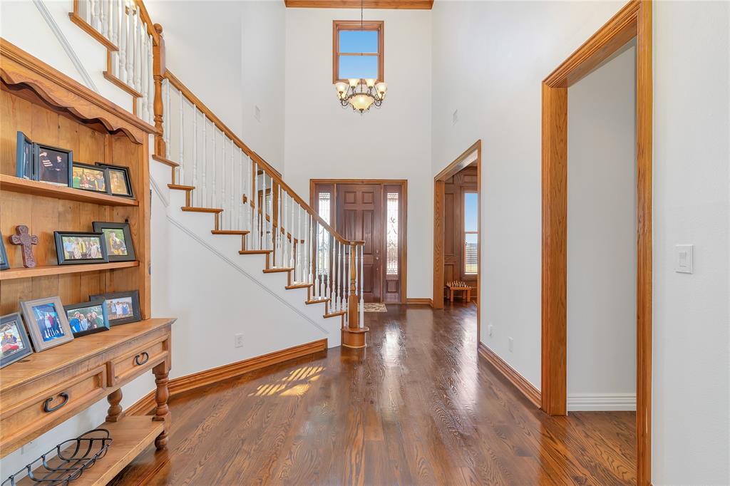 4520 South Nolan River Road Cleburne, TX 76033 - Photo 7 of 40 Entryway featuring wood finished floors, stairway, a high ceiling, an inviting chandelier, and baseboards