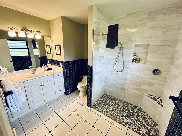 a bathroom with a double vanity sink a toilet a mirror and shower