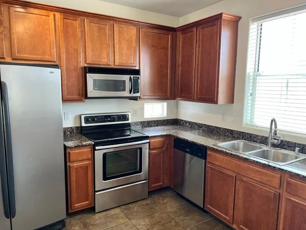 a kitchen with granite countertop wooden cabinets stainless steel appliances and a window