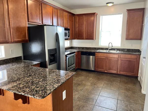 a kitchen with stainless steel appliances granite countertop a sink stove and refrigerator