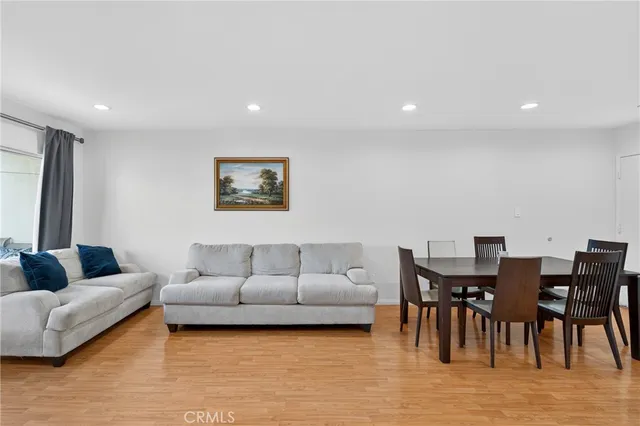 a living room with furniture and a dining table with wooden floor