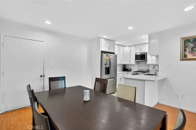 a kitchen with stainless steel appliances granite countertop a sink a stove a refrigerator a dining table and chairs