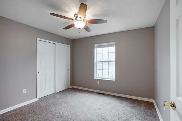 an empty room with chandelier fan and windows