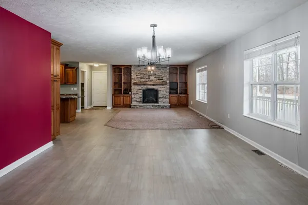 an empty room with fireplace chandelier and windows