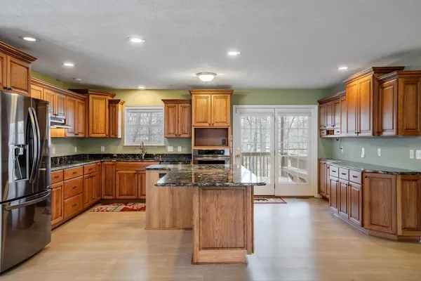 a kitchen with stainless steel appliances granite countertop a refrigerator a stove top oven and a sink with wooden floor