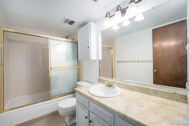 a bathroom with a granite countertop sink toilet and shower