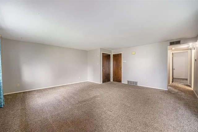 a view of an empty room with closet and entryway