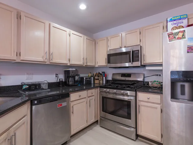 a kitchen with granite countertop white cabinets sink and stainless steel appliances