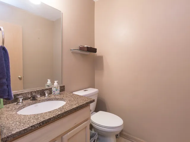 a bathroom with a granite countertop toilet and a sink