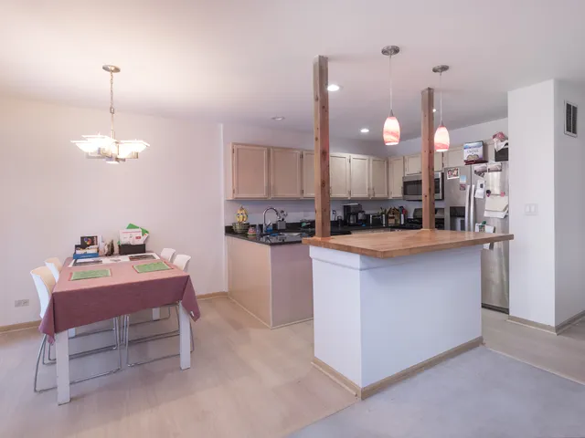 a kitchen with kitchen island stainless steel appliances a dining table chairs sink and cabinets