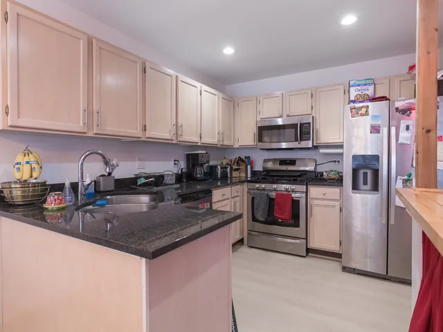 a kitchen with stainless steel appliances granite countertop a stove top oven a sink a refrigerator and dishwasher