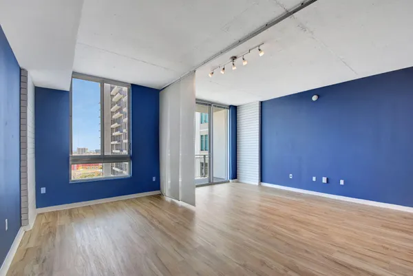 a view of an empty room with window and wooden floor