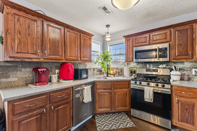 a kitchen with stainless steel appliances granite countertop a stove sink microwave and cabinets