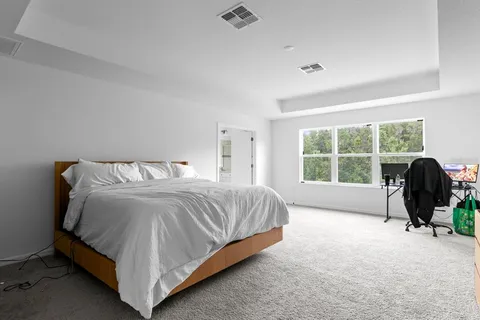 a spacious bedroom with a bed lamp and a large window