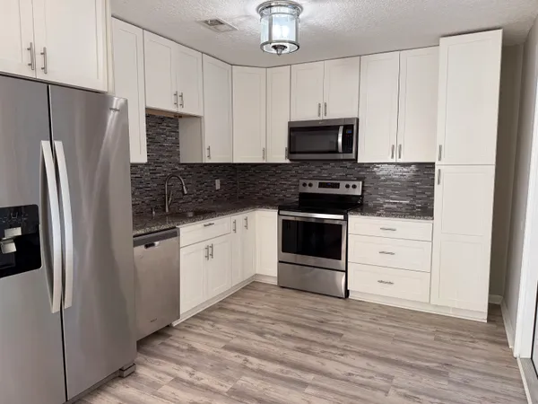 a kitchen with stainless steel appliances white cabinets and a refrigerator