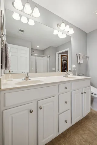 a en suite bathroom with a shower sink and mirror