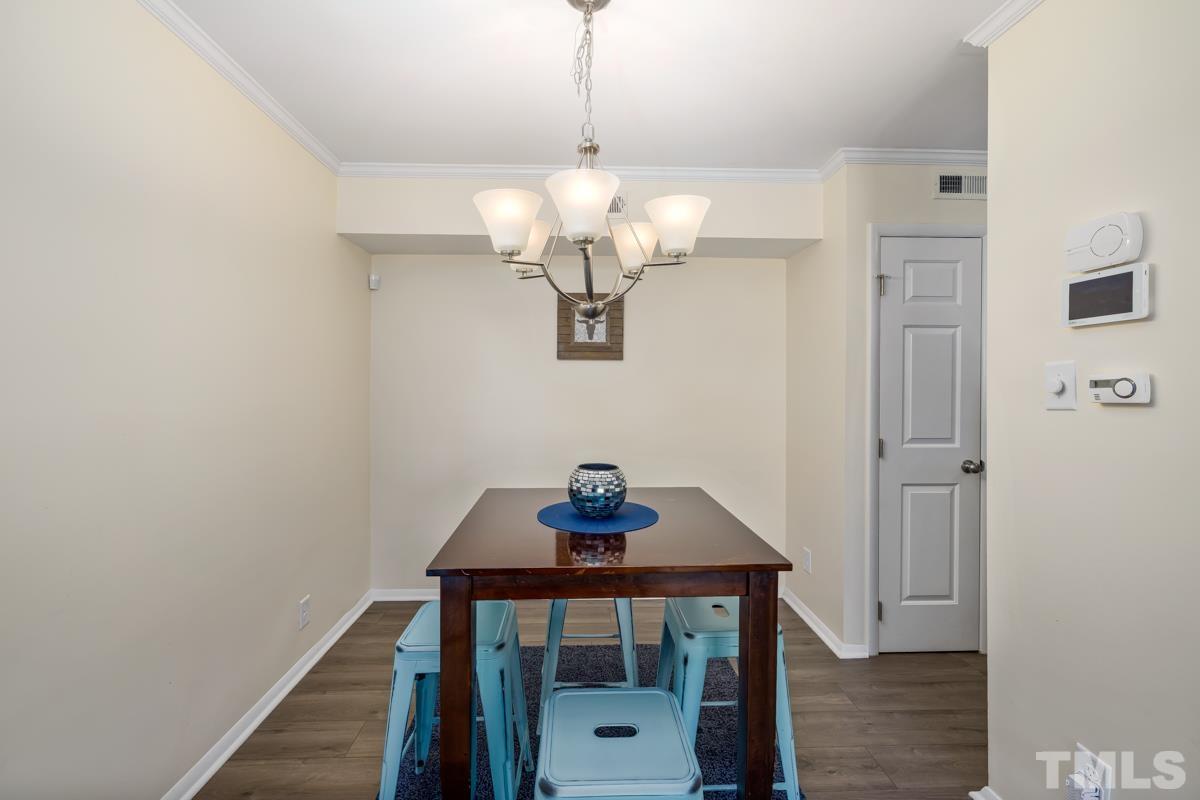 3702 Chimney Ridge Place, Unit 201 Durham, NC 27713 - Photo 9 of 27 a view of a hallway that has a dining table and chandelier