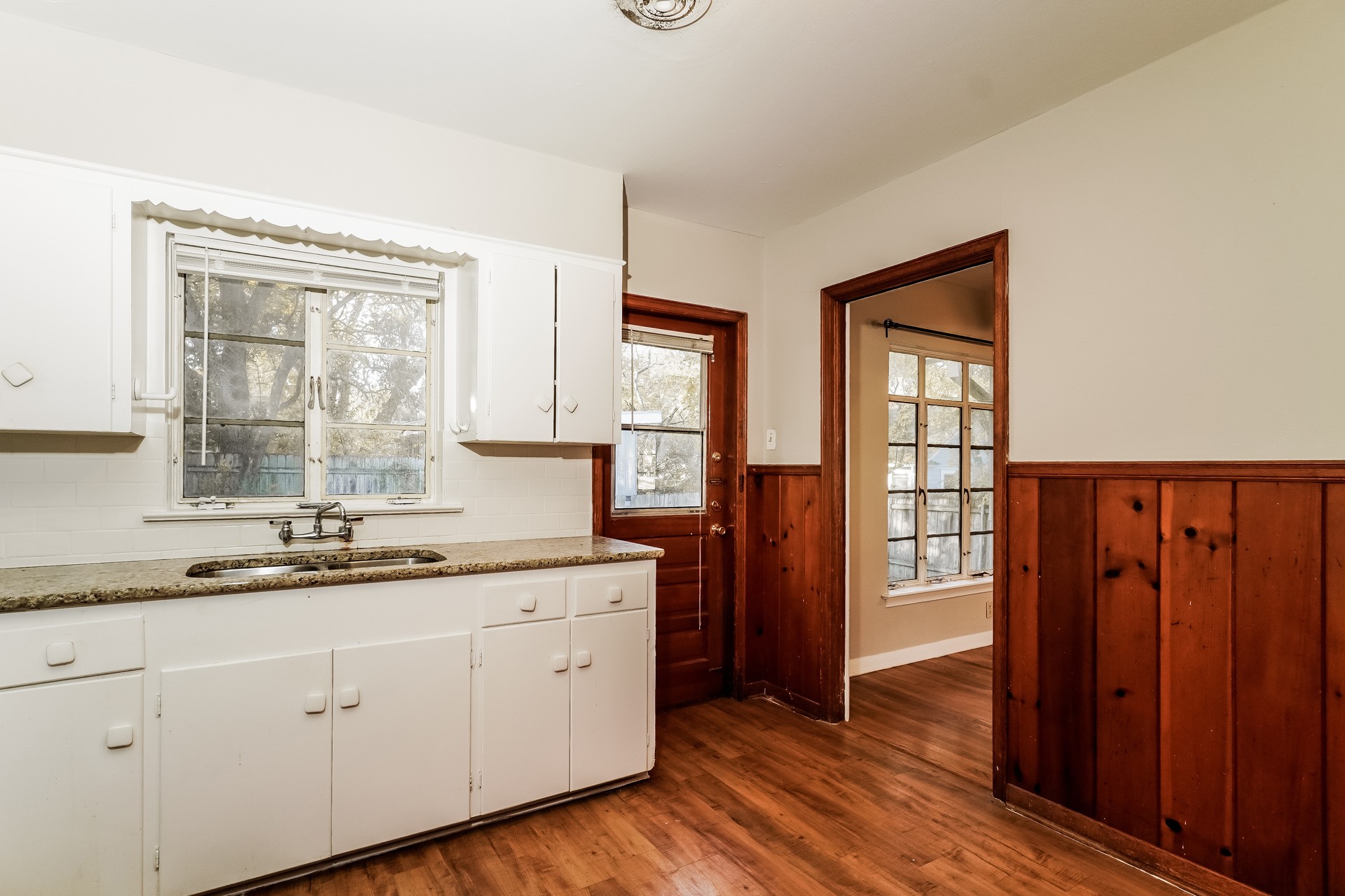 2910 Hampton Road Austin, TX 78705 - Photo 13 of 27 A functional kitchen with wood plank flooring and a classic white cabinet layout.