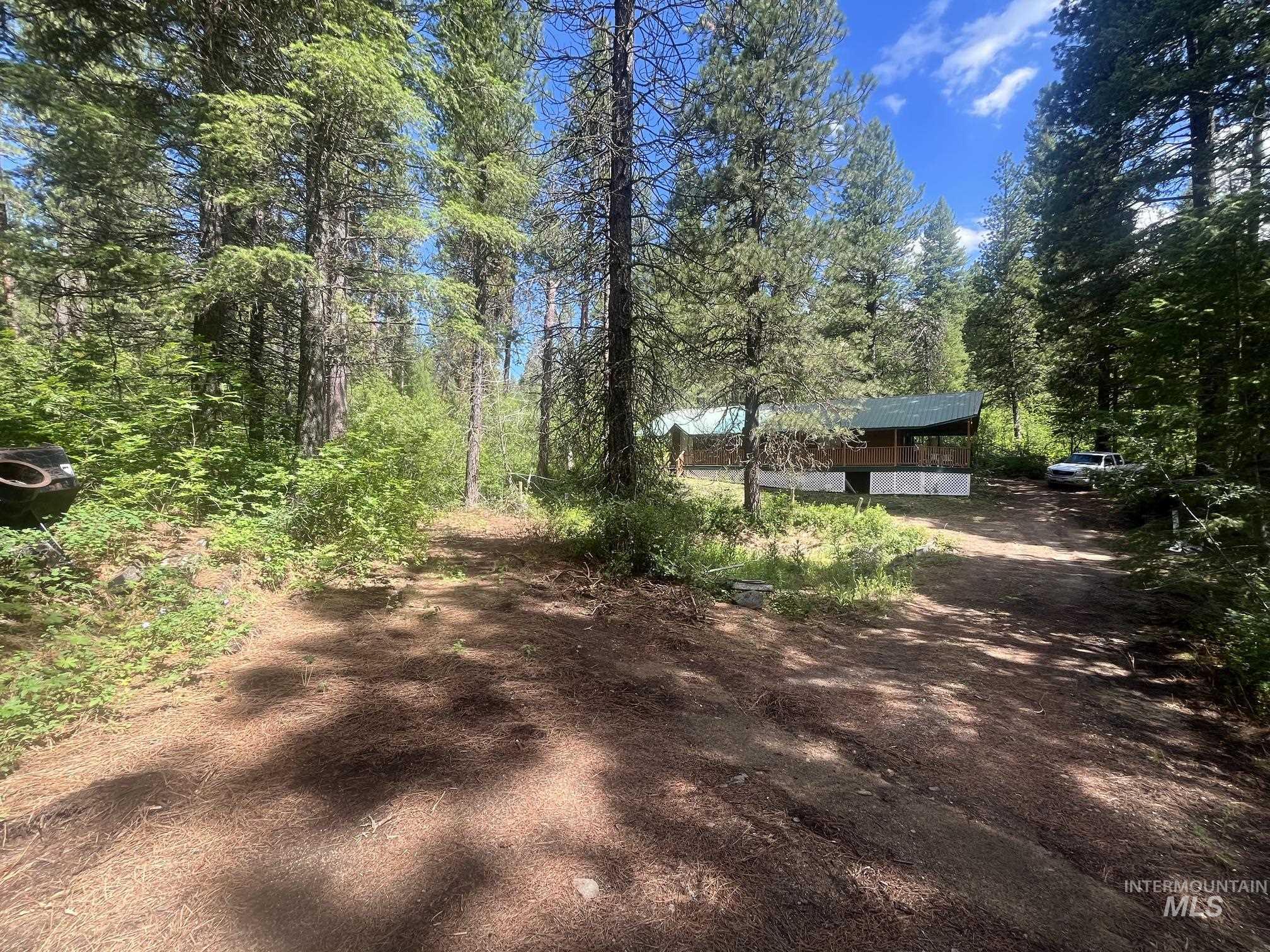 39 Mayflower Mine Road Placerville, ID 83666 - Photo 11 of 36 Wooded property featuring a rustic home with a covered front porch, set amidst mature evergreen trees