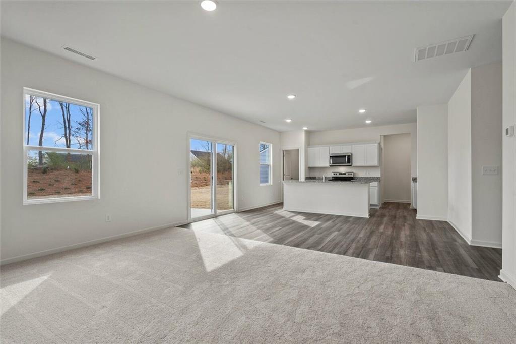 212 Champions Boulevard Dallas, GA 30157 - Photo 8 of 19 a large white kitchen with kitchen island a stove a refrigerator a sink dishwasher with a oven and cabinets with wooden floor