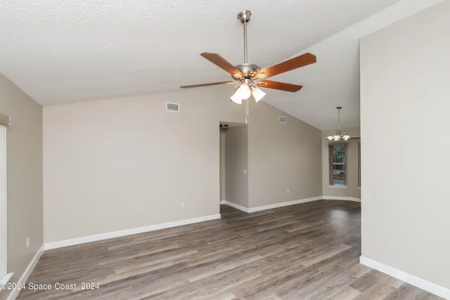 an empty room with wooden floor and ceiling fan