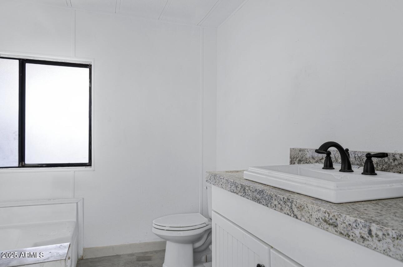 805 North Dysart Road, Unit 33 Avondale, AZ 85323 - Photo 16 of 18 a bathroom with a granite countertop sink and a toilet
