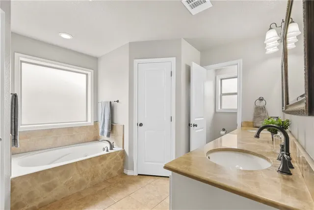 a bathroom with a granite countertop tub sink and mirror