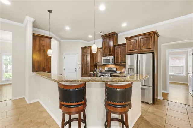 a kitchen with stainless steel appliances granite countertop a refrigerator a stove a sink a dining table and chairs with wooden floor