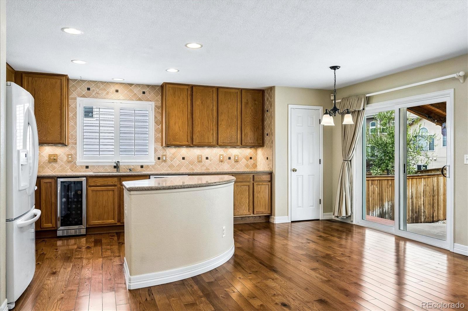 6299 Shannon Trail Highlands Ranch, CO 80130 - Photo 8 of 40 a kitchen with granite countertop wooden floors and white appliances