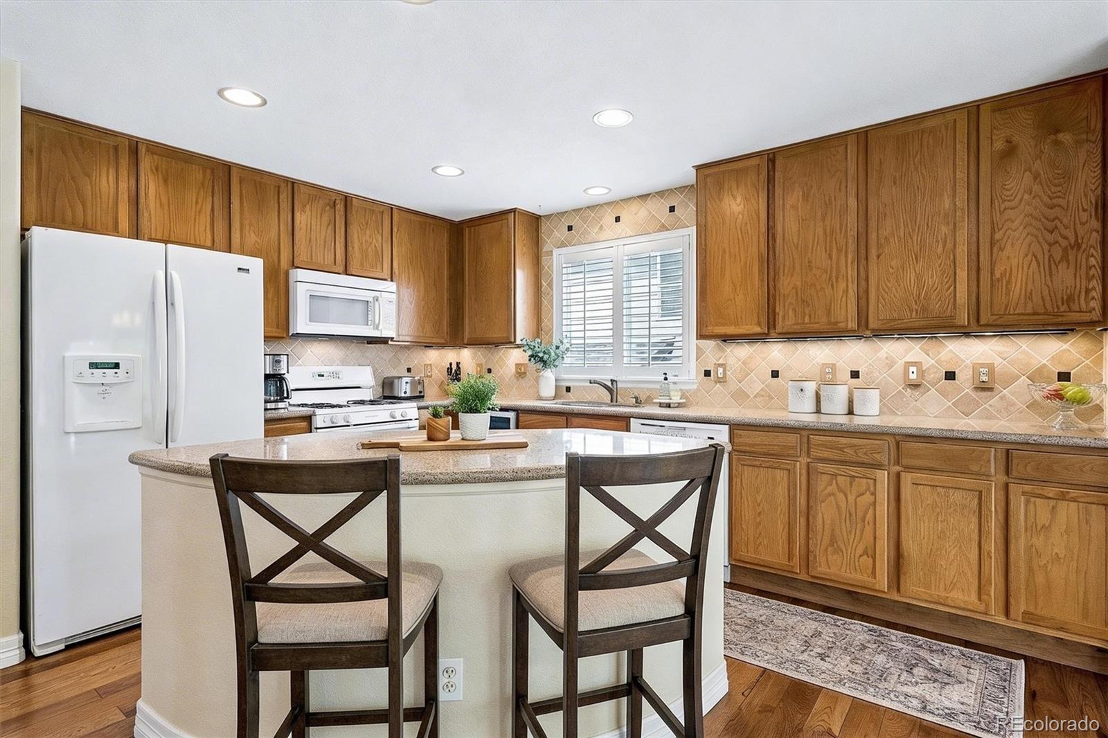 6299 Shannon Trail Highlands Ranch, CO 80130 - Photo 9 of 40 a kitchen with stainless steel appliances kitchen island granite countertop a table chairs sink and cabinets