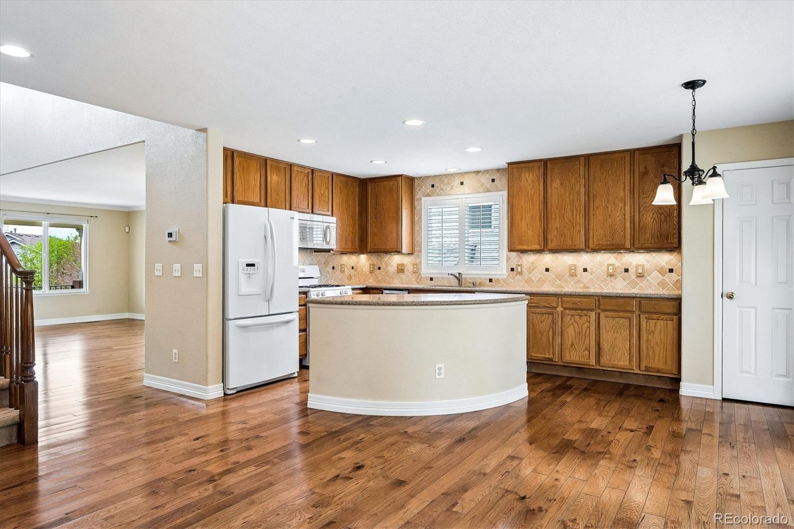 6299 Shannon Trail Highlands Ranch, CO 80130 - Photo 10 of 40 a view of kitchen with stainless steel appliances granite countertop a refrigerator a sink dishwasher a stove with white cabinets and wooden floor