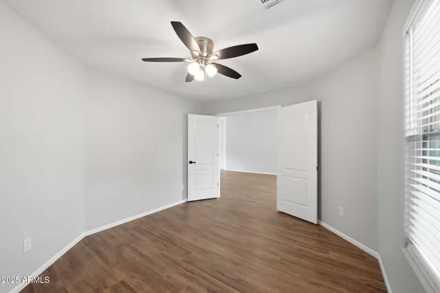 a view of empty room with wooden floor and fan