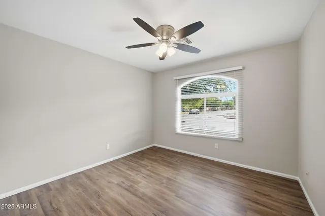 an empty room with wooden floor fan and windows