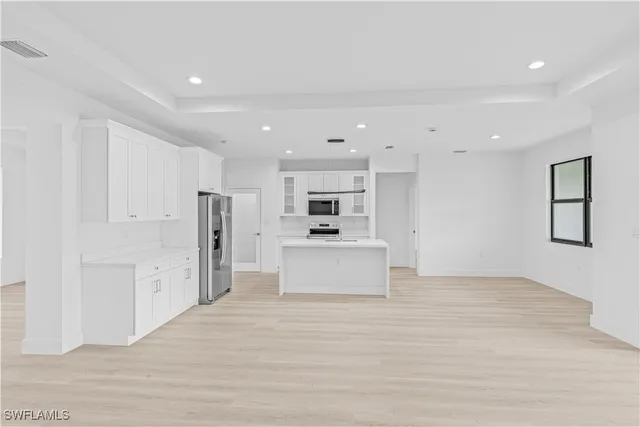 a view of kitchen with stainless steel appliances kitchen island white cabinets and wooden floor