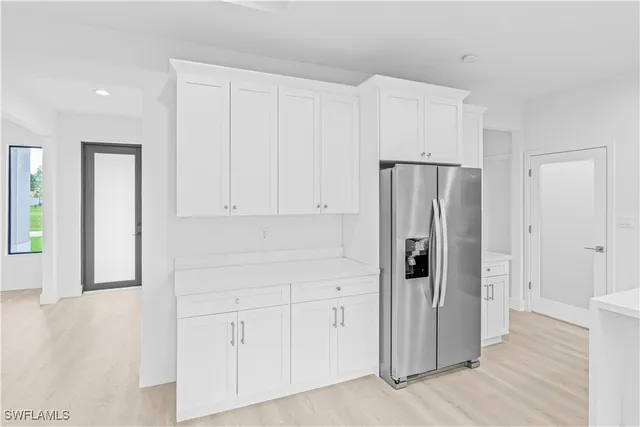 a view of a kitchen with refrigerator and wooden floor
