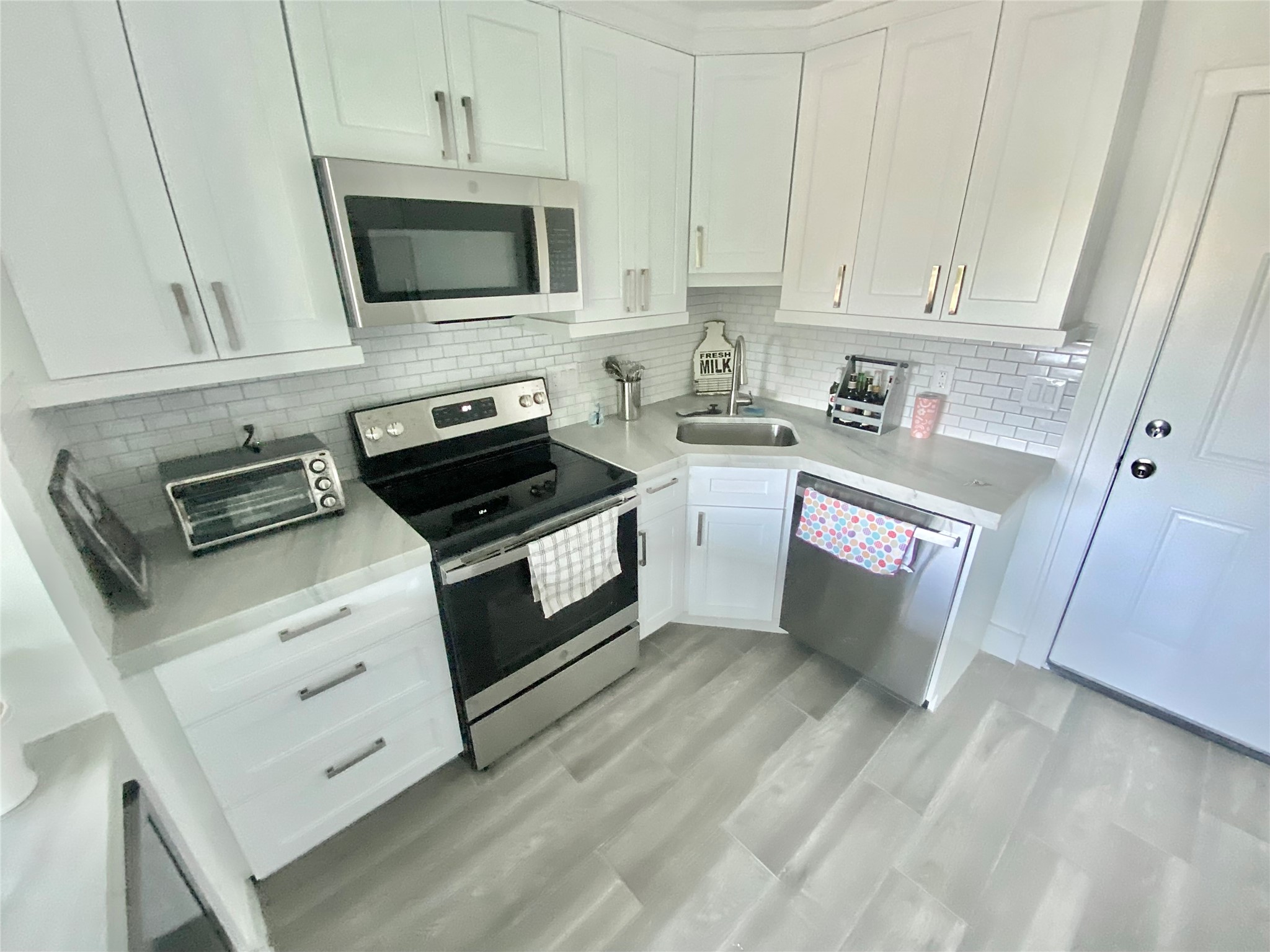 412 Pacific Street, Unit 9E Houston, TX 77006 - Photo 3 of 11 a kitchen with granite countertop a stove a microwave a sink and cabinets
