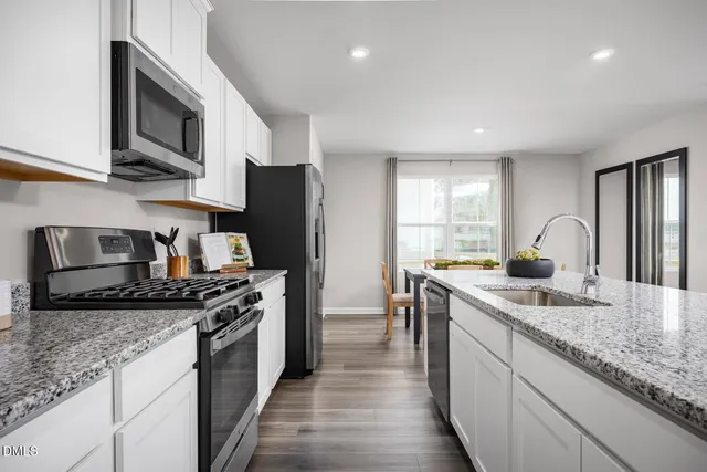 a kitchen with stainless steel appliances granite countertop a table chairs microwave and refrigerator