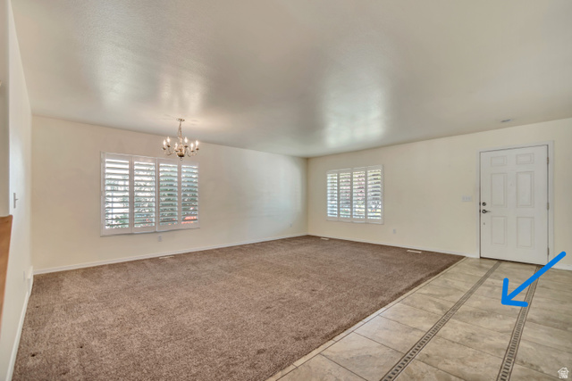 546 Wheatridge Road Tooele, UT 84074 - Photo 9 of 49 Spacious living area featuring neutral carpeting, a custom tile entry with decorative inlay(blue arrow), and