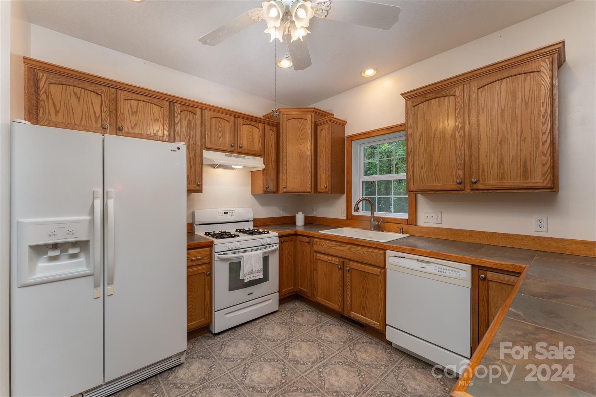 488 Anders Road Zirconia, NC 28790 - Photo 15 of 48 a kitchen with stainless steel appliances granite countertop a refrigerator a sink dishwasher a stove and white countertops with wooden floor