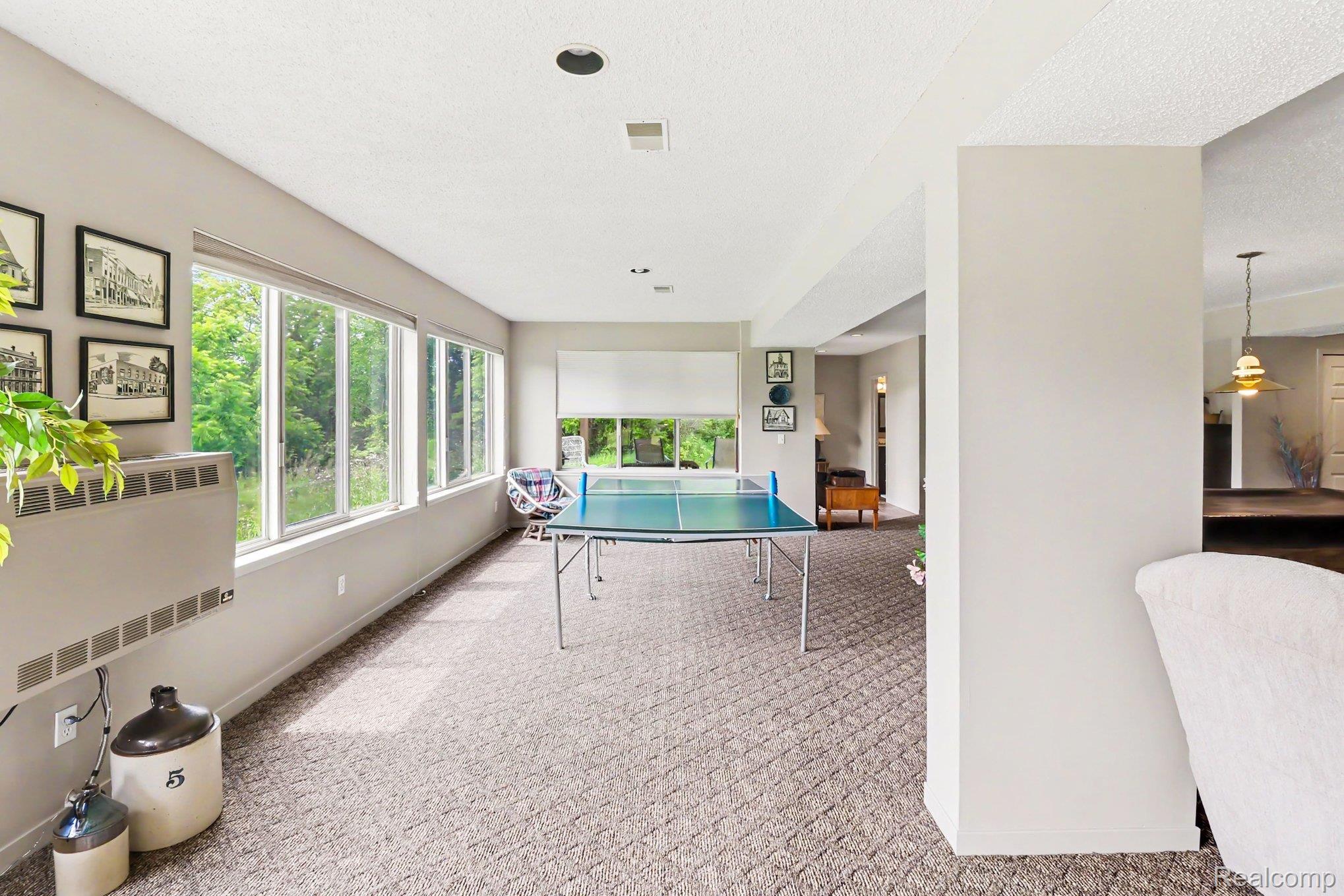 18501 Taylor Lake Road Holly, MI 48442 - Photo 30 of 35 Recessed lighting illuminates a spacious room featuring a wall of multiple windows, textured carpeting, and a built-in wall heater