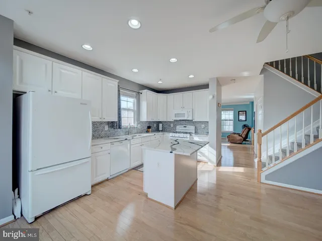 a kitchen with granite countertop white cabinets and white appliances