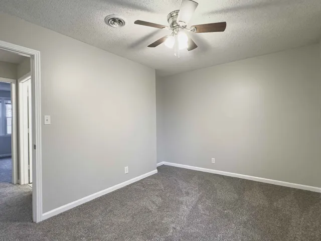 an empty room with a window and a fan