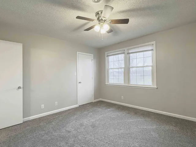an empty room with windows and fan