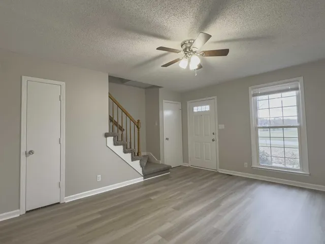 a view of an empty room with wooden floor and a window
