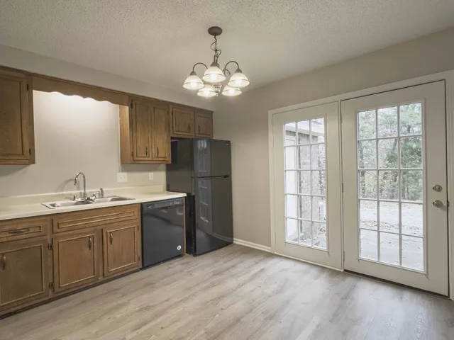 a kitchen with stainless steel appliances granite countertop a refrigerator a sink dishwasher a dining table and chairs with wooden floor