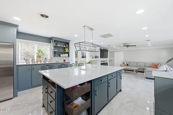 a large kitchen with granite countertop a stove a sink dishwasher a dining table and chairs with wooden floor