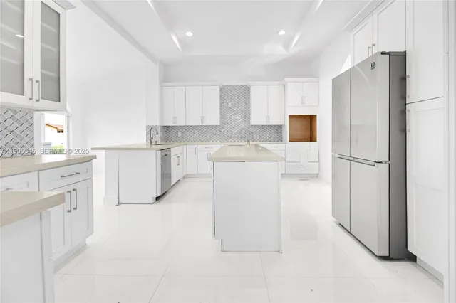 a kitchen with white cabinets and refrigerator