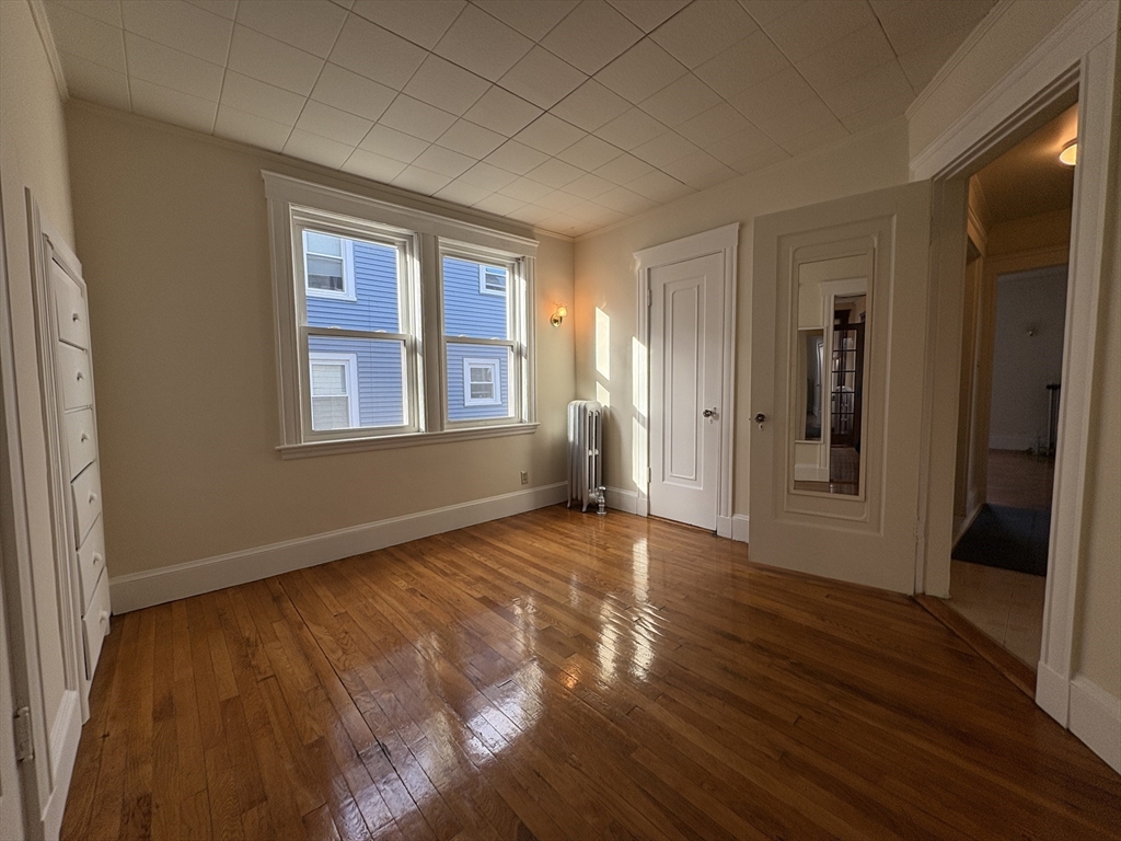 155-157 Hillside Street, Unit 1 Boston, MA 02120 - Photo 11 of 18 a view of an empty room with wooden floor and a window