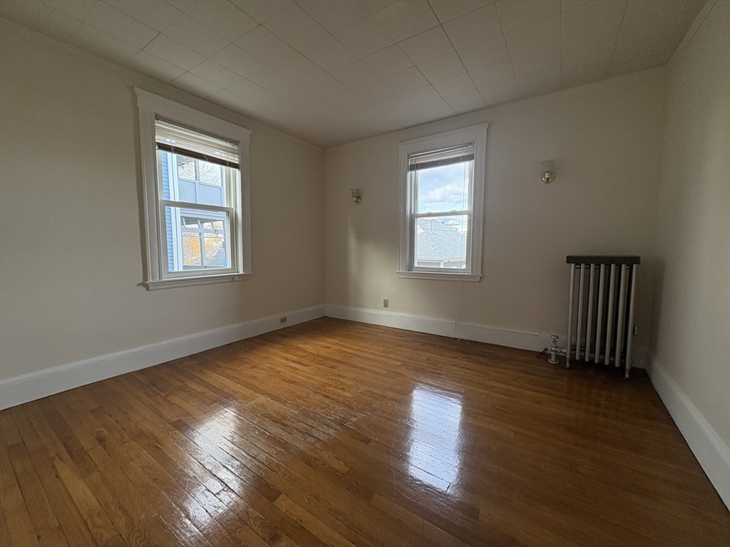 155-157 Hillside Street, Unit 1 Boston, MA 02120 - Photo 14 of 18 an empty room with wooden floor and windows