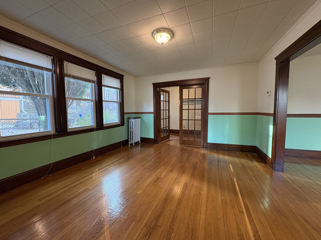 155-157 Hillside Street, Unit 1 Boston, MA 02120 - Photo 5 of 18 a view of an empty room with wooden floor and a window